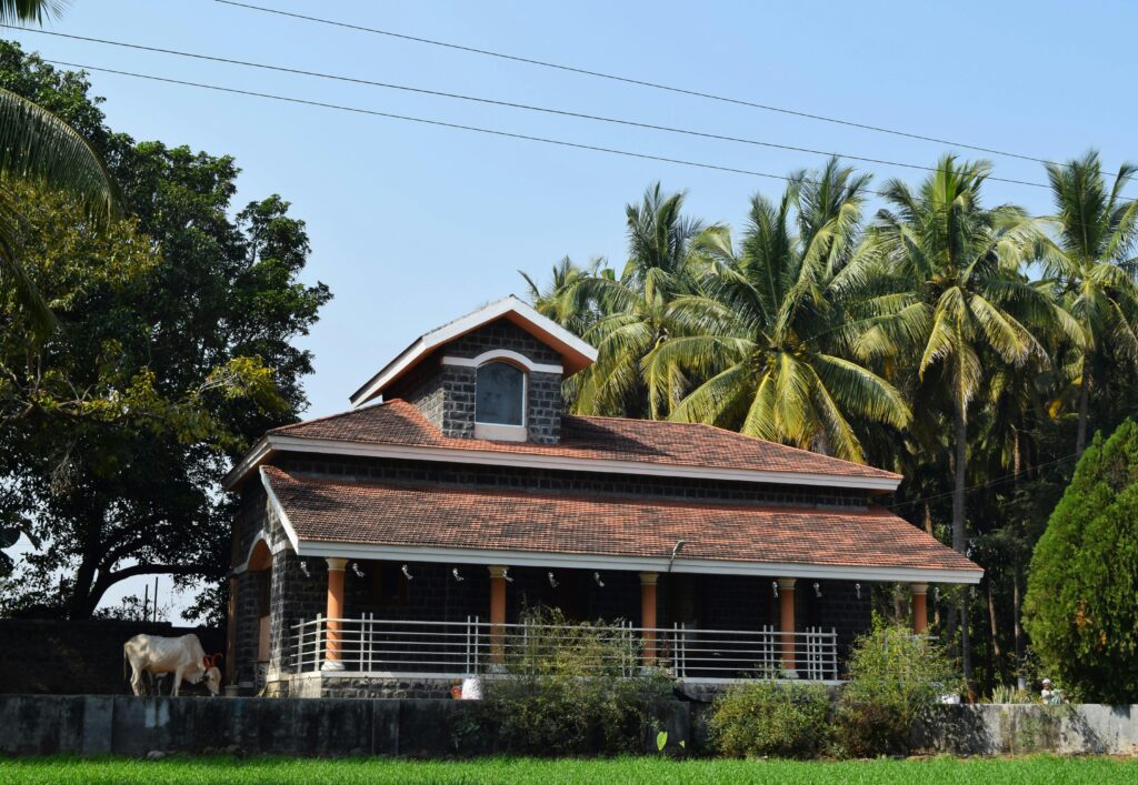 A beautiful rural house with a red roof and palm trees, showcasing serene countryside life.